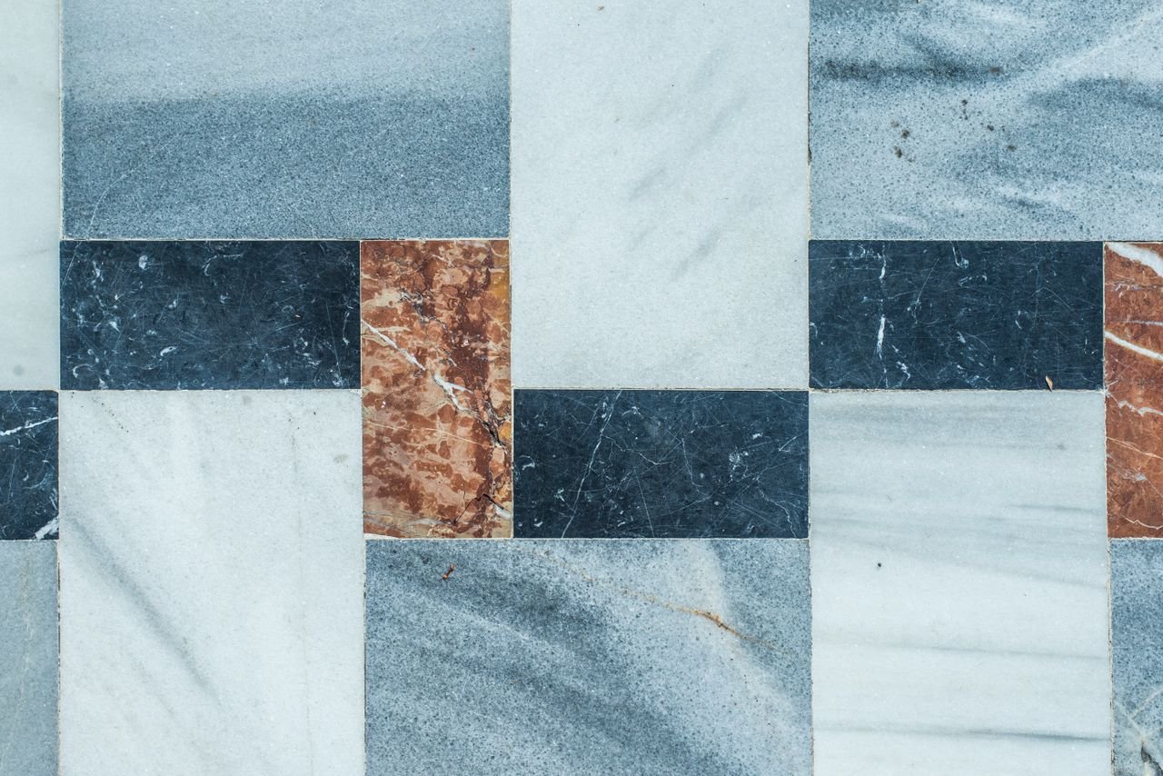 quality-assurance-01 Close-up of a geometric marble tile pattern with natural texture colors.