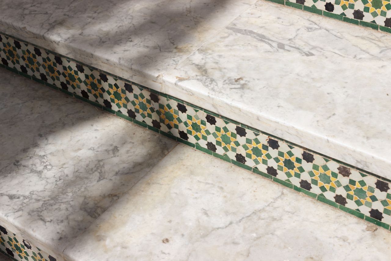 social-feed-img-03 Detailed view of marble steps adorned with intricate mosaic tiles casting soft shadows.
