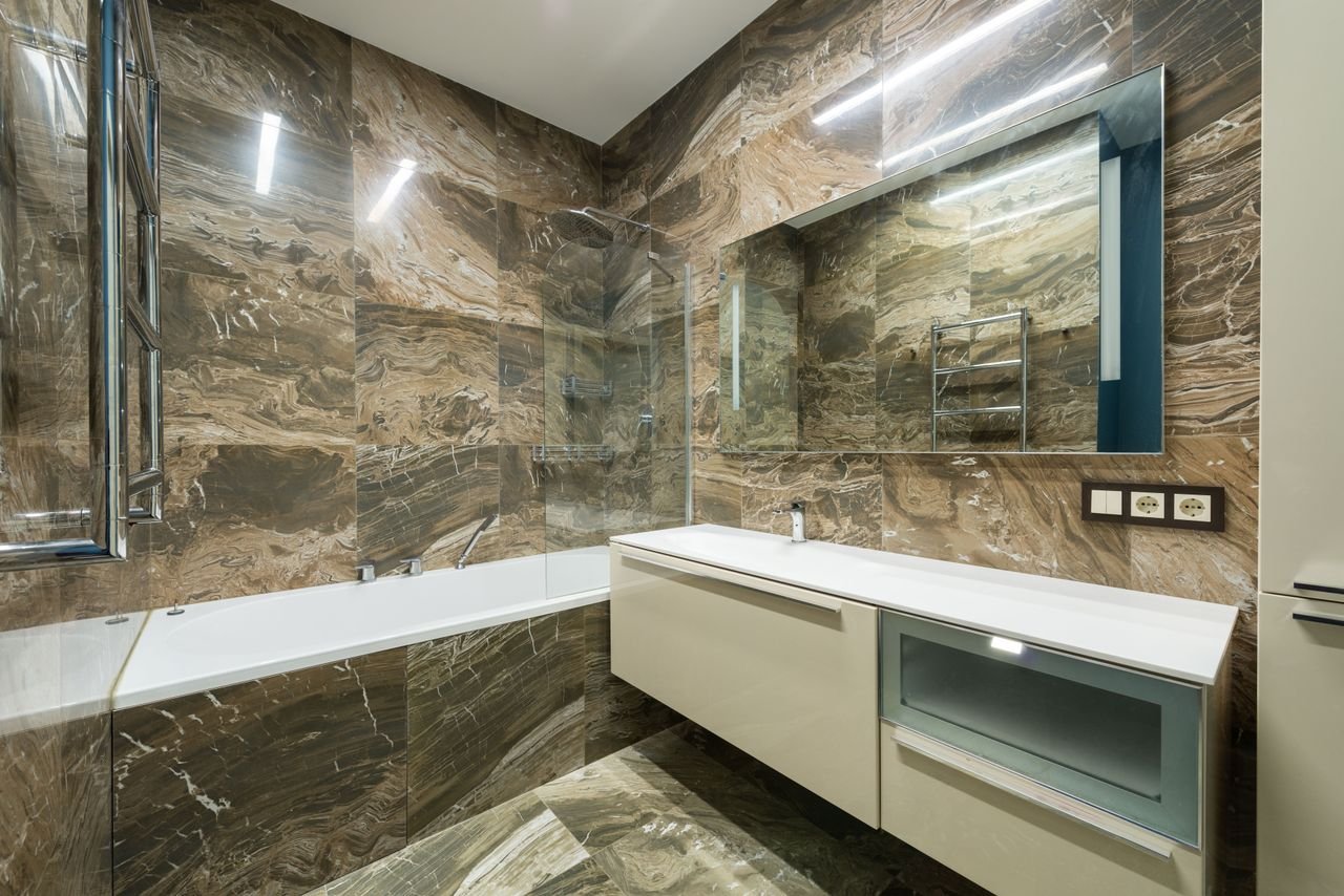 social-feed-img-02 Bathtub placed near wall sink on cabinet at wall with mirror placed in contemporary bathroom with marble tiles at home